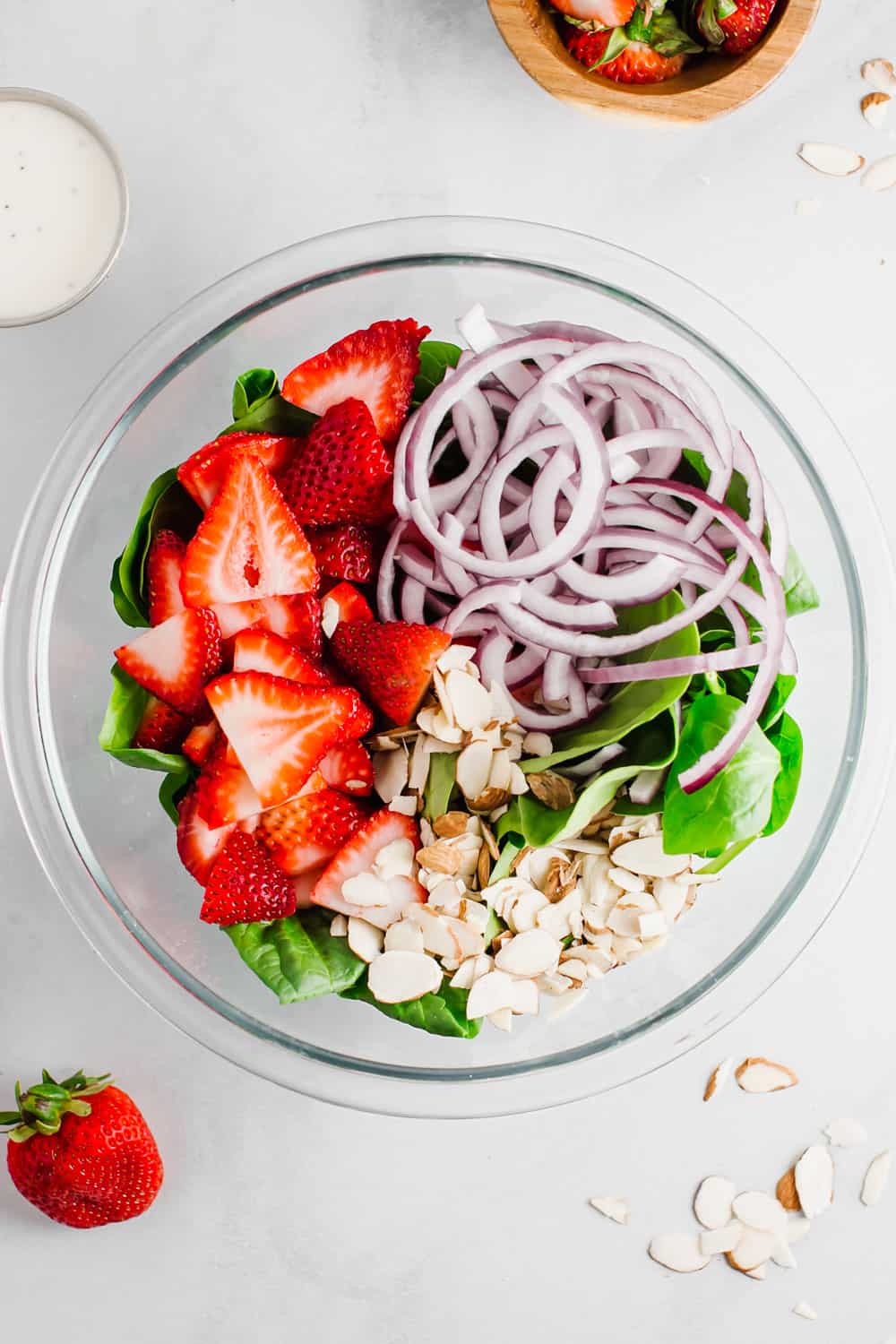 Strawberry spinach saladย is a perfect combination of fresh spinach, juicy strawberries, crunchy onions, and soft feta cheese; all tossed together with a creamy poppyseed dressing! All the flavor, texture, andย deliciousness in one bowl! A bowl of ingredients ready to be mixed.