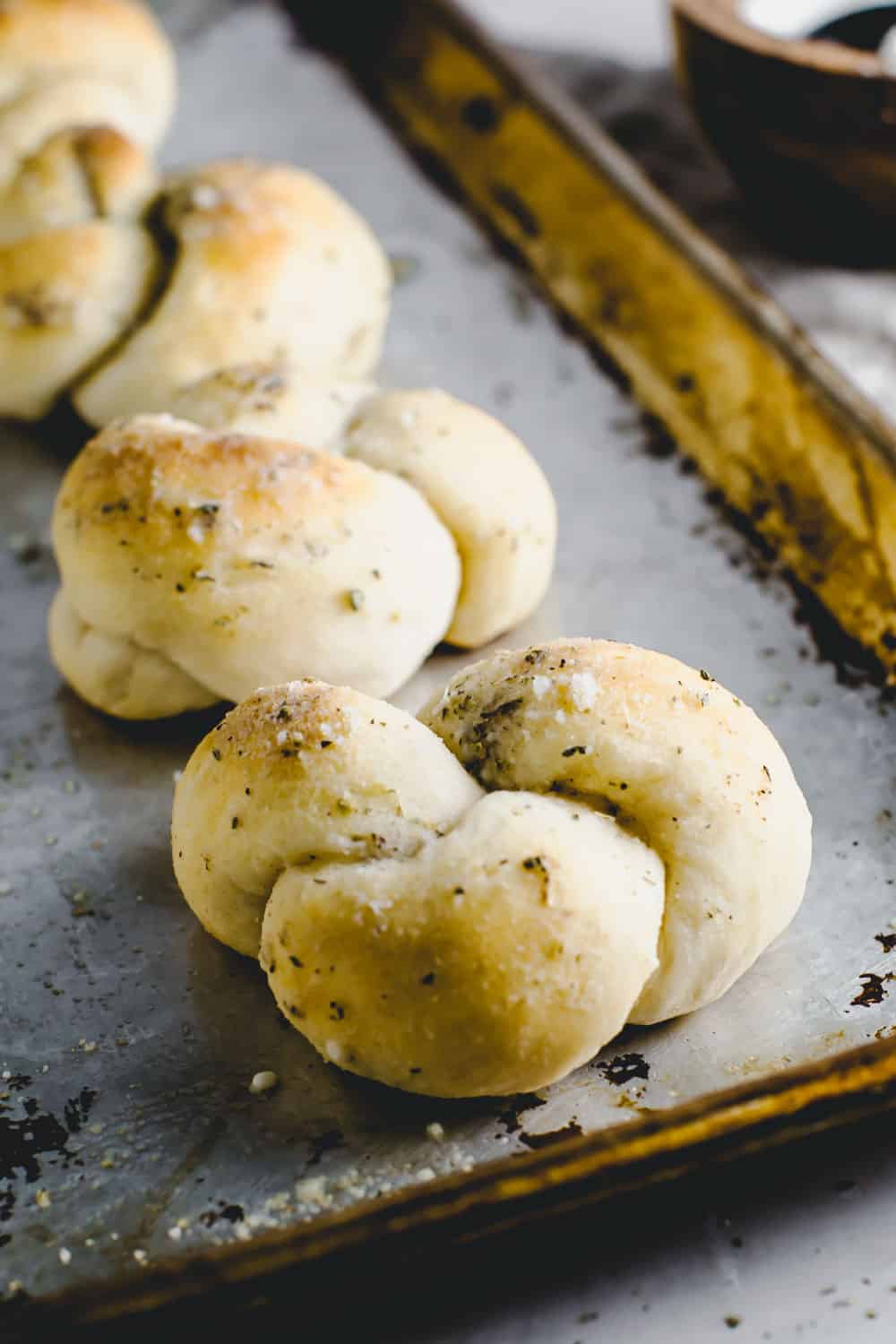 Easy Parmesan Knots are quickย and simple warm, buttery garlic knots that twist to perfection in 20 minutes! These won't last long at the dinner table!ย Parmesan knots on a baking sheet