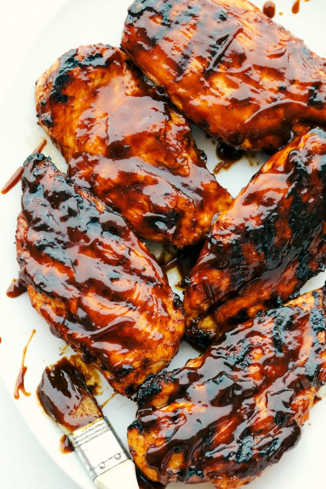 This grilled BBQ chicken is a simple to make tender chicken that's coated in a sweet homemade barbecue sauce that comes through with great flavor in every bite!ย You will be making this weekly after you see what a huge hit it is! Grilled BBQ chicken covered in barbecue sauce.