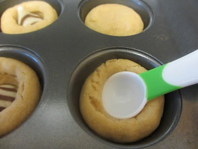 This cookie recipe is probably one of the best that I have tried because the cookie part is so soft! It stays soft for a couple days after you make them! A spoon pushing down the dough in a muffin tin to make a space for the Hershey's Kisses.