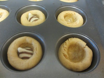 This cookie recipe is probably one of the best that I have tried because the cookie part is so soft! It stays soft for a couple days after you make them! Close up photo fo muffin tin with dough with the Hershey's Kisses put in the center of the dough.
