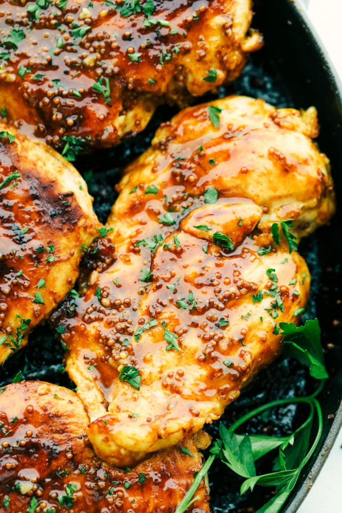 Grilled Honey Mustard chicken is tender and juicy grilled chicken covered in a sweet and tangy sauce with a punch of spice. It is simple to prepare and so flavorful. The fresh and perfectly balanced flavors of the honey mustard will be a staple in your summer BBQ plans! Up close photo of grilled honey mustard chicken on the grill.