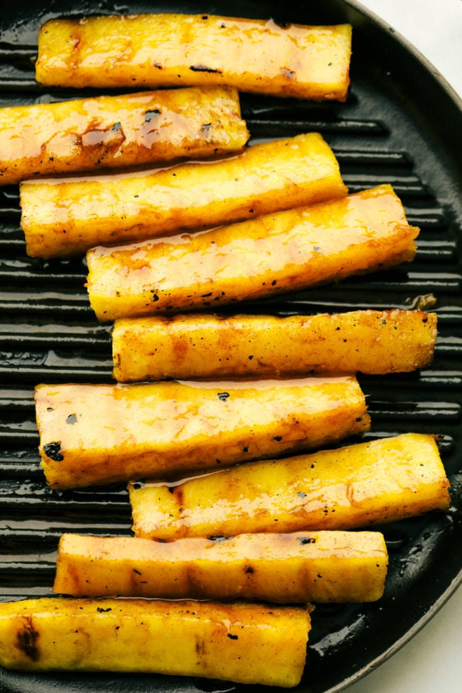 Pineapple spears that get coated in a buttery brown sugar cinnamon glaze and caramelize on the grill! Thisย will be one of the most amazing sides that you grill this summer! Pineapple spears on a grilling pan.