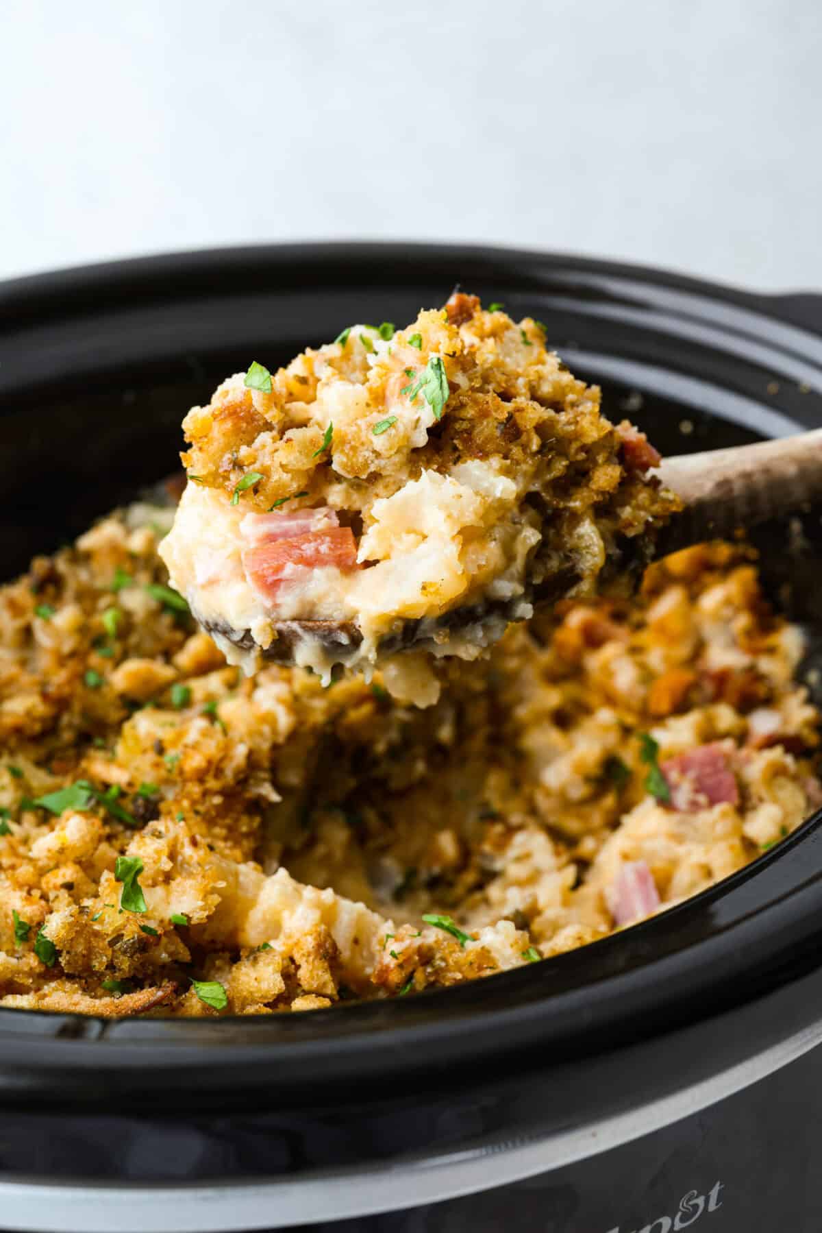 Toss your leftover ham in the slow cooker with potatoes, melty cheese, and buttery stuffing for my ridiculously easy Slow Cooker Ham and Potato Casserole! Close up shot of a scoop of Slow Cooker Ham and Potato Casserole!