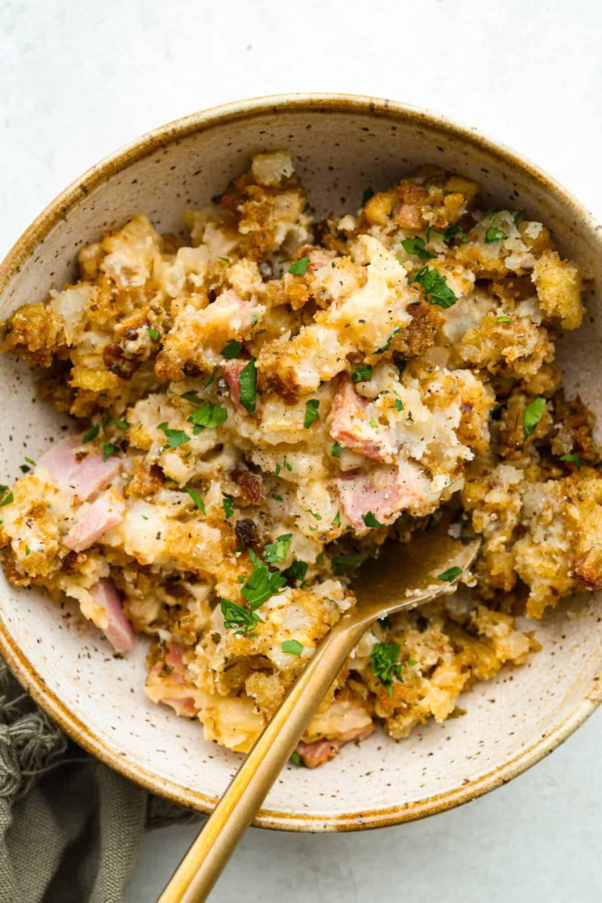 Toss your leftover ham in the slow cooker with potatoes, cheese, and buttery stuffing for my ridiculously easy Slow Cooker Ham and Potato Casserole! Overhead shot of a bowl of slow cooker ham and potato casserole.