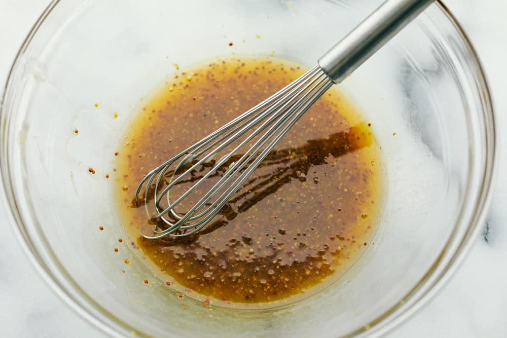 Honey Butter Baked Chicken is a rich and flavorful dinner that has tender baked chicken made with only four ingredients! The blend of honey and butter is the perfect combination for a flavorful chicken dinner.ย A glass bowl of ingredients being whisked together.