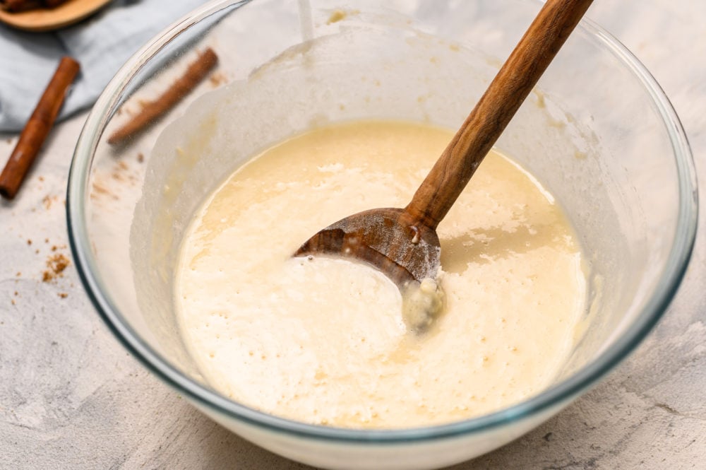Mini Peach cobbler is the perfect warm, sweet dessert to satisfy any sweet tooth.ย The flaky crust and sweet fruit filling will have you liking the spoon! Especially when you top it with some creamy vanilla ice cream! Cobbler dough mix being stirred by a wooden spoon in a glass bowl.
