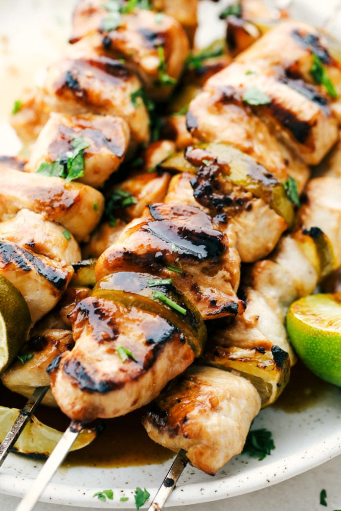 Grilled Key Lime Chicken is tender and juicy chicken drenched in key lime flavor and grilled to perfection on a skewer. It is quick and easy to make and enjoy with your family on a warm summer night! Grilled Key Lime Chicken on skewers on a white plate.