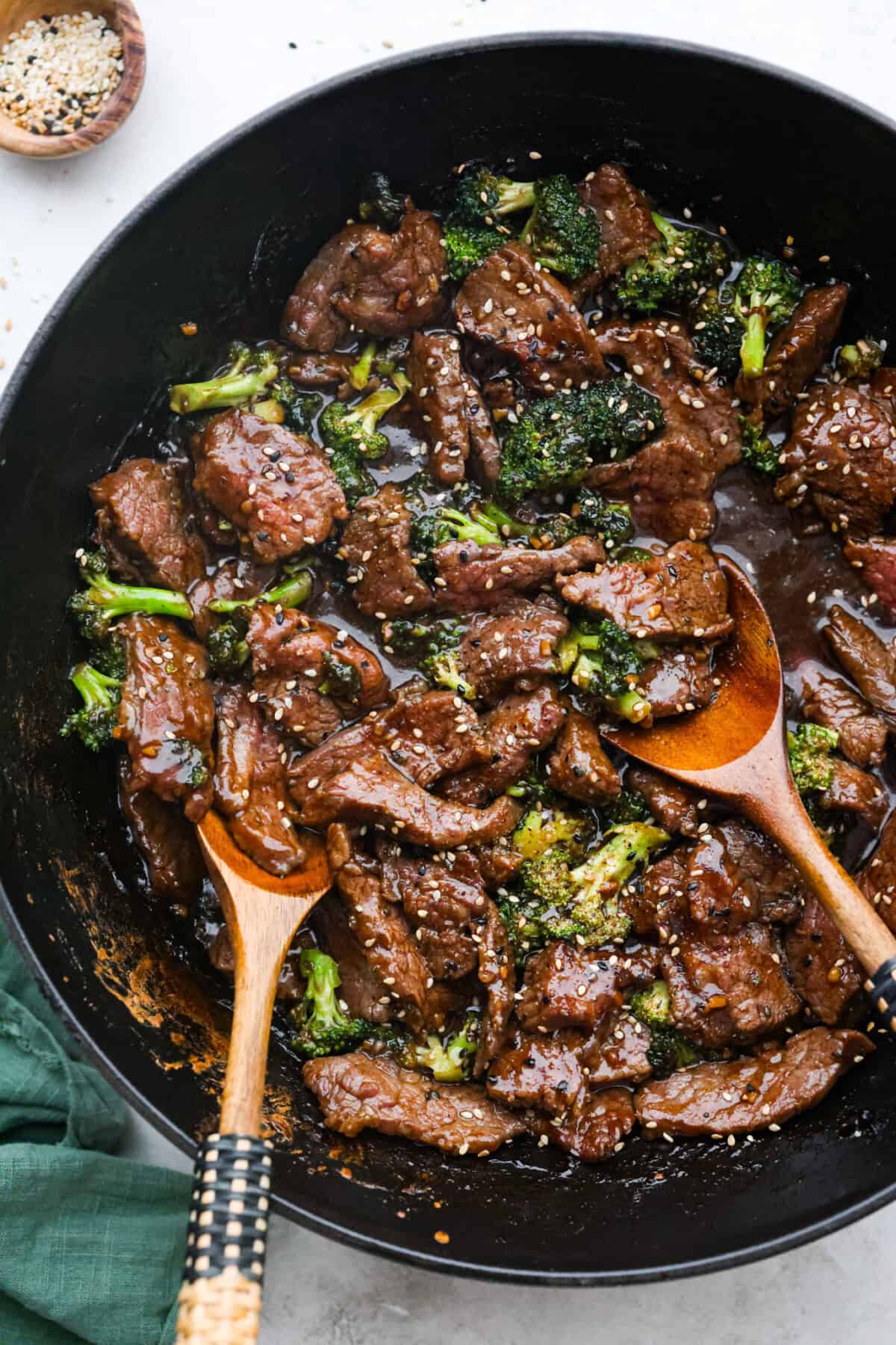 This Mongolian beef and broccoli recipe is the best P.F. Chang’s copycat recipe. You will love the combination of tender beef, vibrant broccoli and intensely flavorful sauce. Save yourself money while making your family happy with this quick and easy recipe. Overhead shot of Mongolian beef and broccoli in a skillet with wooden serving spoons.