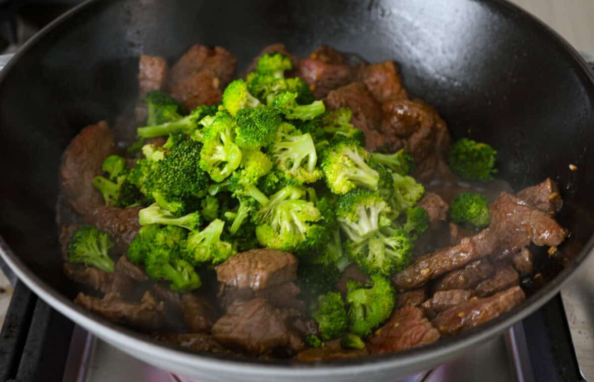 This Mongolian beef and broccoli recipe is the best P.F. Chang’s copycat recipe. You will love the combination of tender beef, vibrant broccoli and intensely flavorful sauce. Save yourself money while making your family happy with this quick and easy recipe. Overhead shot of broccoli and flank steak sautéing in a skillet.