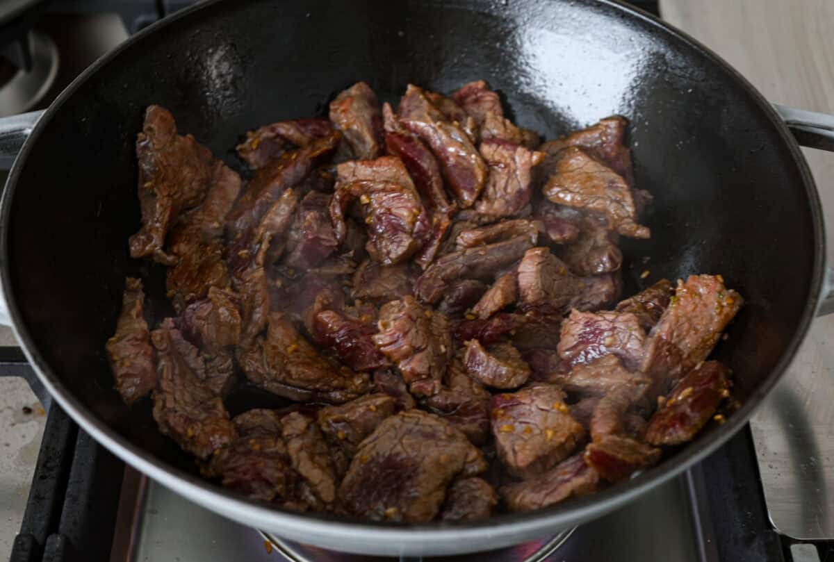 This Mongolian beef and broccoli recipe is the best P.F. Chang’s copycat recipe. You will love the combination of tender beef, vibrant broccoli and intensely flavorful sauce. Save yourself money while making your family happy with this quick and easy recipe. Overhead shot of flank steak sautéing in a skillet.