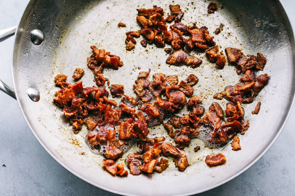 Creamy Bacon Carbonaraย is a classic Italian creamy pasta. Bacon, mushrooms, and onions are cooked together and tossed in aย cheesy, rich egg yolk sauce for an easy 30 minute meal! A quick and easy dinner that is made in minutes! bacon on the skillet