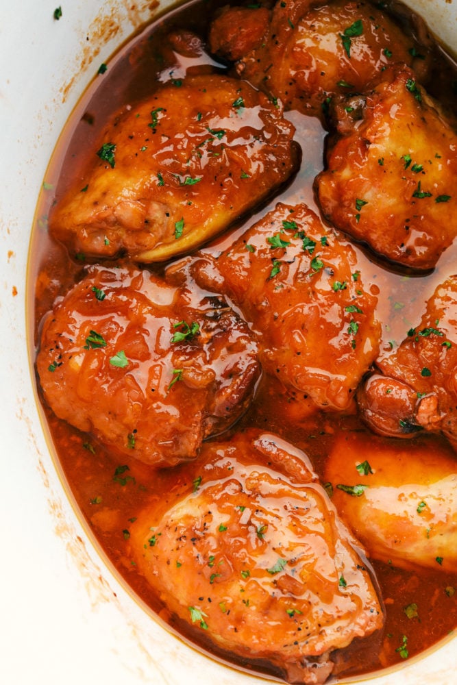 Apricot chicken is a super easy and incredibly delicious dinner your whole family is going to love! Tender, juicy chicken covered in a sweet and savory glaze. It only takes 4 ingredients to make, and all you have to do is throw everything in your slow cooker! Itโs the perfect hearty weeknight meal. Top-down view of apricot chicken in a white serving dish.