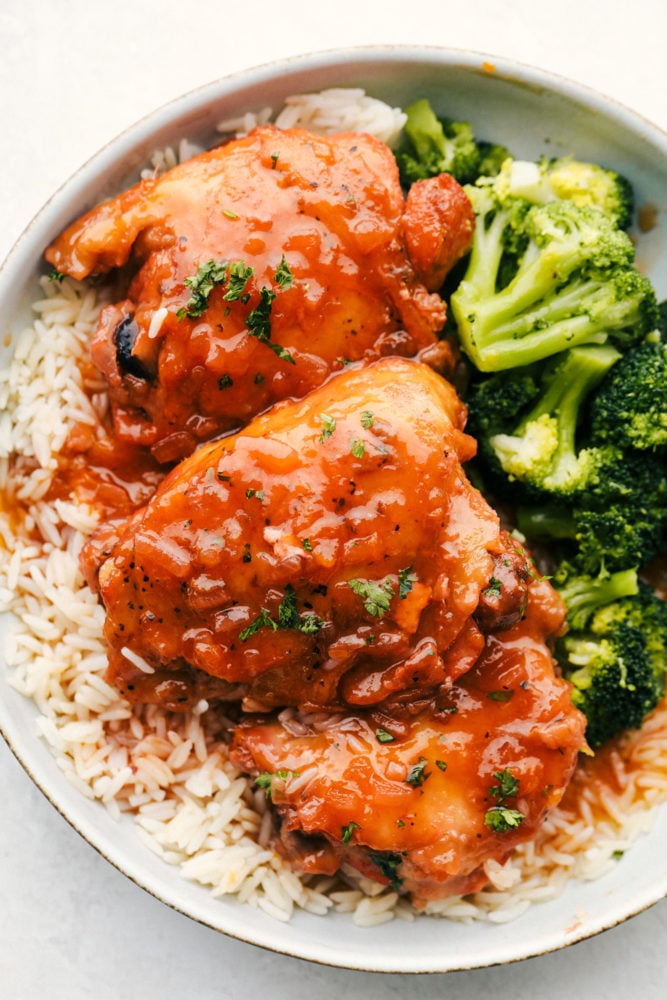 Apricot chicken is a super easy and incredibly delicious dinner your whole family is going to love! Tender, juicy chicken covered in a sweet and savory glaze. It only takes 4 ingredients to make, and all you have to do is throw everything in your slow cooker! Itโs the perfect hearty weeknight meal. Top-down view of apricot chicken served with rice and broccoli on a white plate.
