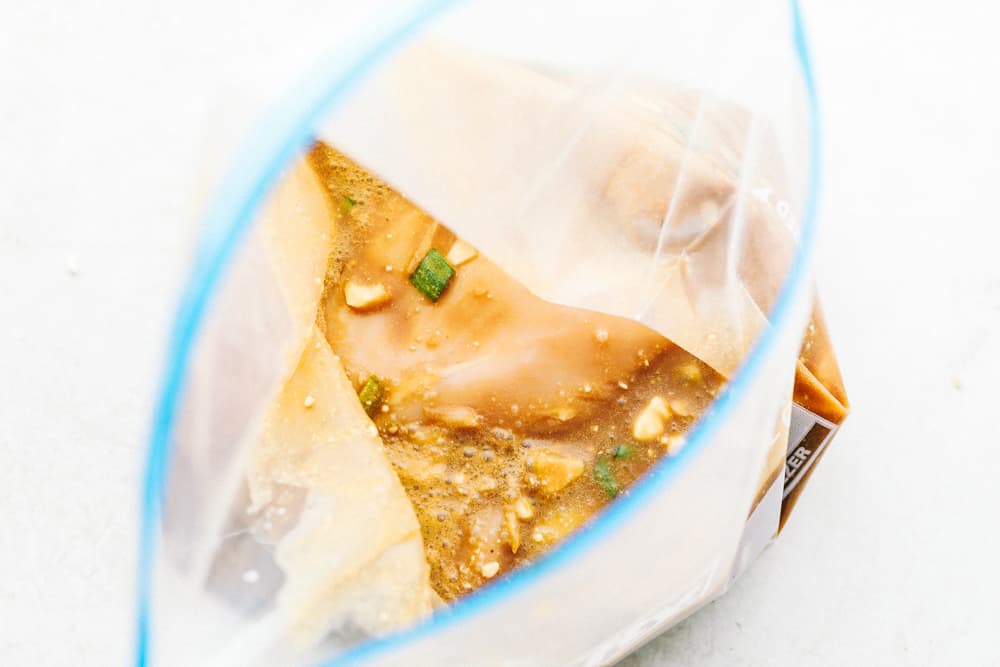 This Hawaiian chicken is marinated in a rich, flavorful sweet and savory sauce that tenderizes the chicken then grilled to perfection. Imagine being in Hawaii with this summertime favorite!ย An open ziplock bag with marinade in it and chicken breasts.
