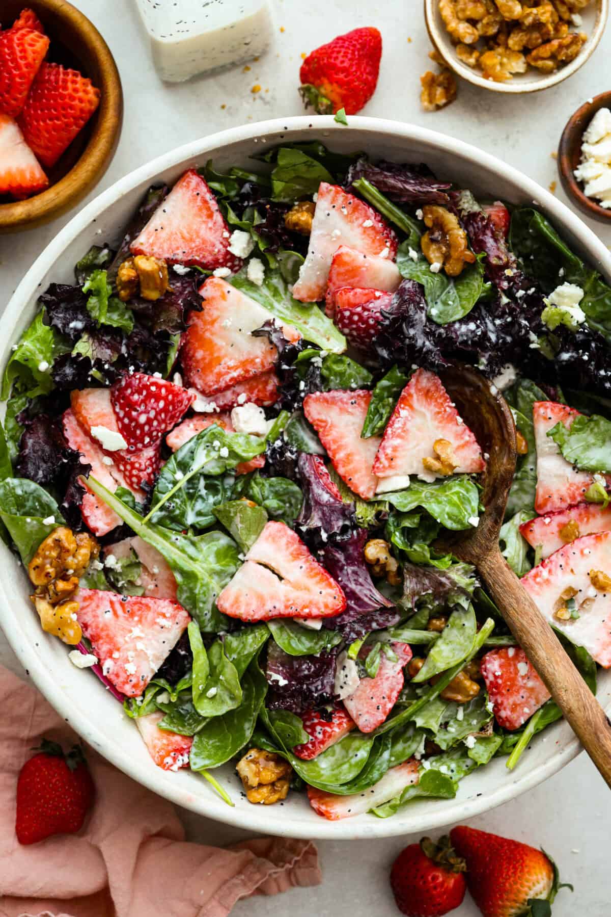 This Strawberry Spinach Salad is my FAVORITE spring salad! The juicy strawberries and candied walnuts add the best texture. Toss it with my creamy poppyseed dressing and you have the prettiest salad at the table! Overhead shot of a large bowl of strawberry spinach salad with glazed walnuts dressed and ready to eat.