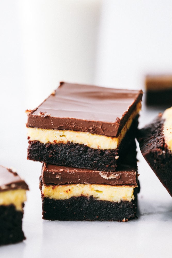 This delicious Hershey's chocolate cheesecake brownies are layered with a moist, homemade chocolate cake with a creamy cheesecake filling topped with a thick Hershey chocolate layer making this irresistible. Heaven on a plate! Hershey chocolate cheesecake brownies stacked on top of each other.