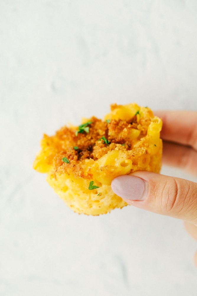 Mac and Cheese cups are a great twist on a classic side and are made of soft pasta coated in creamy, cheesy sauce and baked to perfection in a muffin pan to make serving a breeze.ย These are a huge hit and everyone will rave about them! Close up on a mac and cheese muffin.