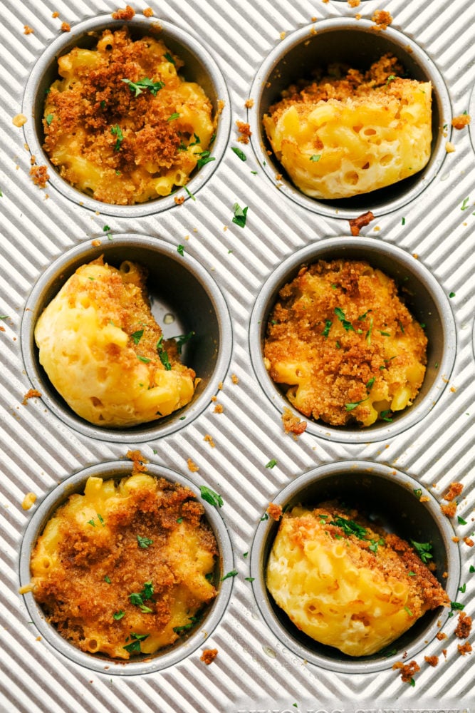 Mac and Cheese cups are a great twist on a classic side and are made of soft pasta coated in creamy, cheesy sauce and baked to perfection in a muffin pan to make serving a breeze.ย These are a huge hit and everyone will rave about them! Finished mac and cheese cups in a muffin tray.
