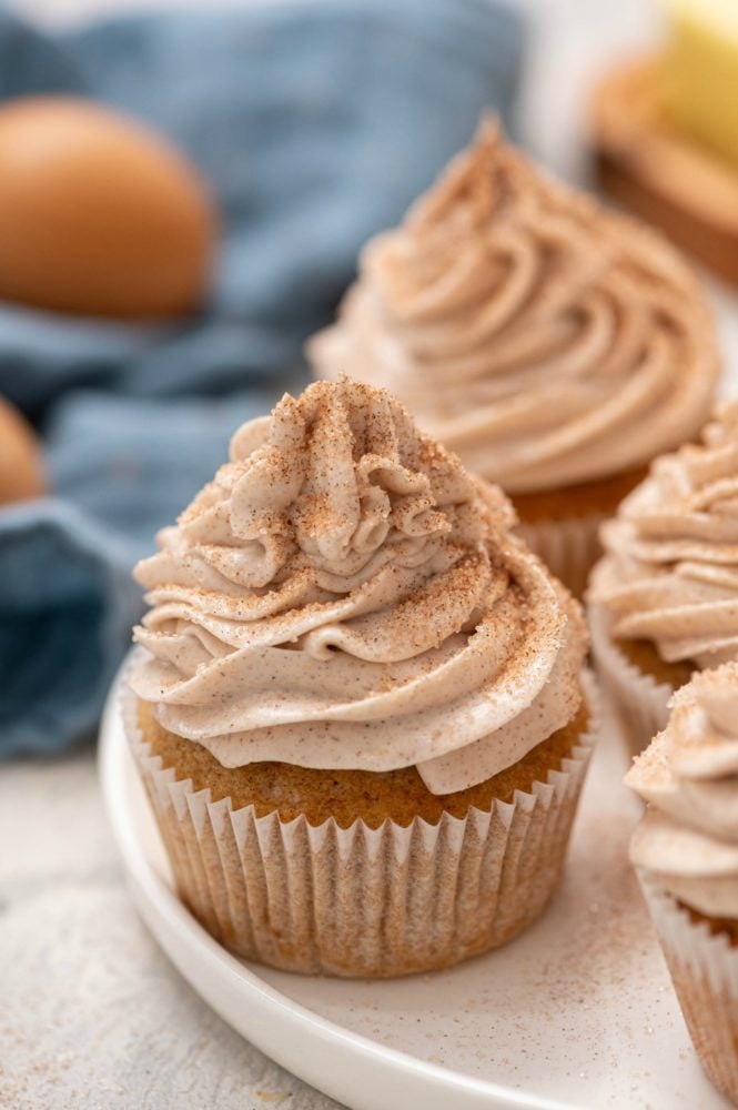 Churro Cupcakes are fluffy and light cinnamon sugar cupcakes that are easy to make and even easier to fall in love with!ย They are made with common baking ingredients that you may even have in your pantry right now! Churro cupcakes on a white plate.