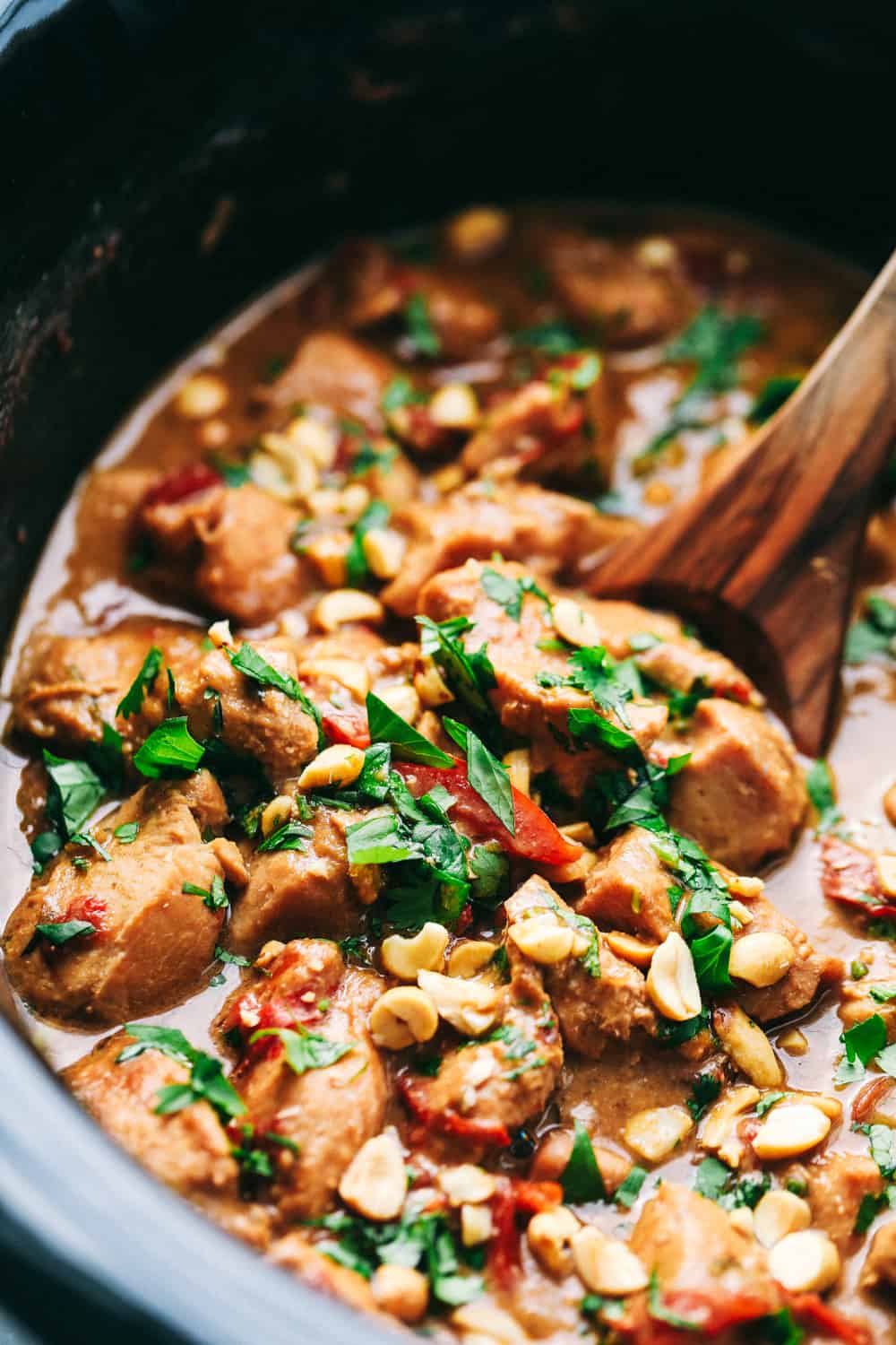Slow Cooker Thai Peanut Chicken is a creamy, peanut flavor infused chicken that is served over thick, rich noodles. Easy to make in just a couple steps adding all the ingredients together letting the slow cooker do the work for you! Enjoy the smells that will fill your home while cooking during the day. Slow cooker Thai Peanut Chicken being stirred in a pot.