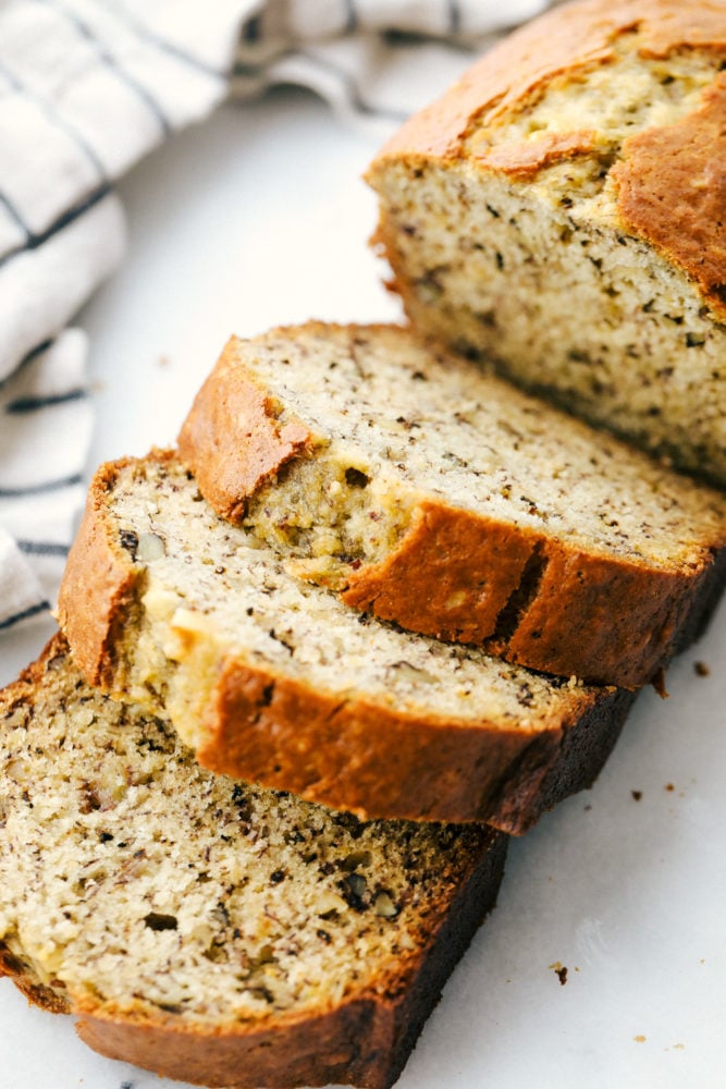 Treat yourself with a slice of thick, rich, and moist banana bread. This is the easiest way to make it! It's full of flavor and always a hit with the family. Top-down view of banana bread cut into slices.