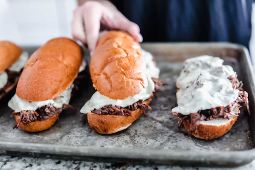 Slow Cooker French Dip Sandwiches are filled with tender chunks of roast beef with thin slices of melted mozzarella cheese all held together by a soft hoagie bread all dipped in au jus sauce. This warm, savory and comforting sandwich is a MUST! baking the slow cooker French dip sandwiches