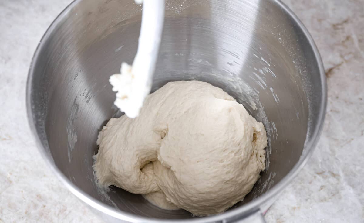Homemade breadtwists have all the delicious buttery, garlic flavor of your favorite restaurant-quality breadsticks, but now they are unbelievably easy to make at home!ย The smell that fills your home will make you want to eat them straight out of the oven! Overhead shot of dough ball in the bottom of a stand mixer bowl.