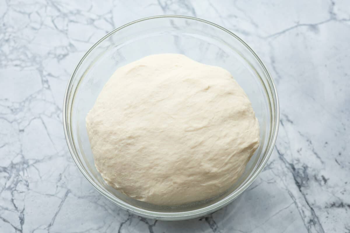 Homemade breadtwists have all the delicious buttery, garlic flavor of your favorite restaurant-quality breadsticks, but now they are unbelievably easy to make at home!ย The smell that fills your home will make you want to eat them straight out of the oven! Overhead shot of dough ball in a glass bowl.