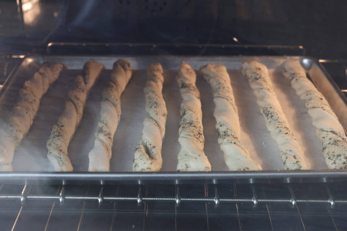 Homemade breadtwists have all the delicious buttery, garlic flavor of your favorite restaurant-quality breadsticks, but now they are unbelievably easy to make at home!ย The smell that fills your home will make you want to eat them straight out of the oven! View of homemade breadtwists on a baking sheet in the oven.