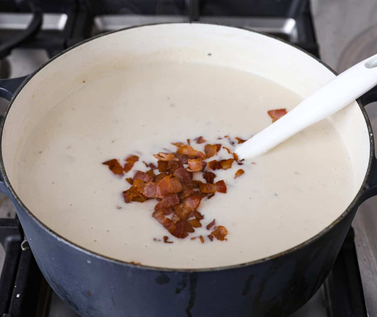 Creamy Potato Soup is the ultimate comfort food. It has a velvety, creamy base with blended potato, tender potato bites, onions, and garlic, all topped with crispy bacon! It's the perfect meal to cozy up with on a cold day. Close up shot of the creamy potato soup covered in crispy bacon bits.