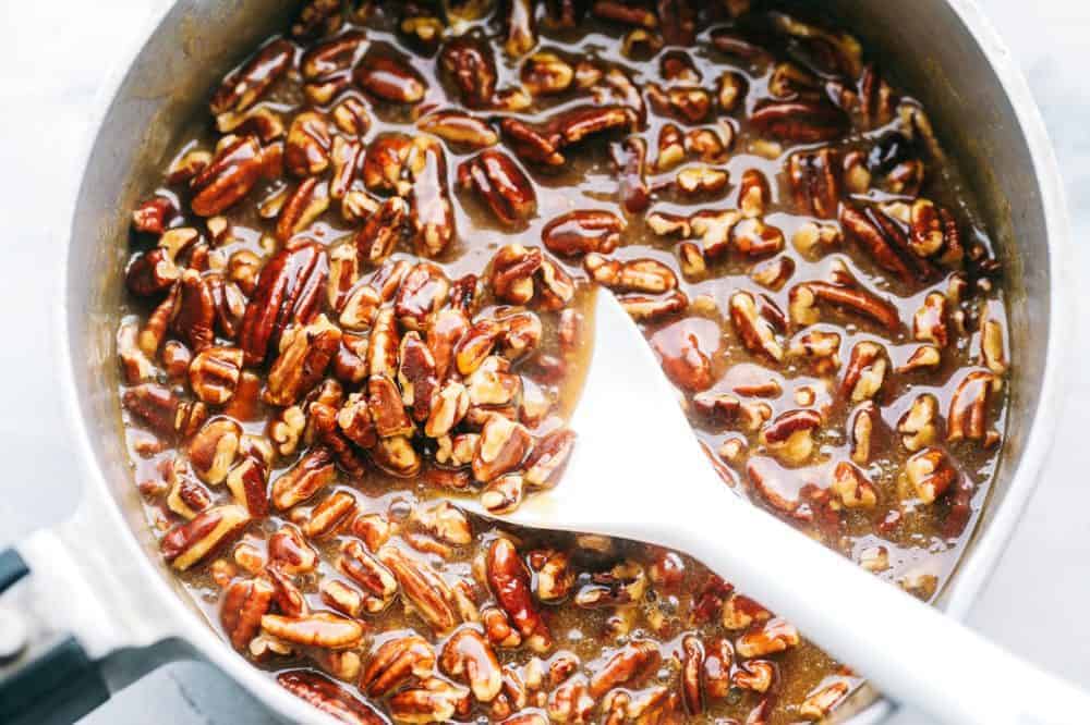 Best Ever Pecan Pie Bars takes the amazing pecan pie and transforms it into irresistible bars. A buttery shortbread crust that gets topped with a caramel pecan glaze, these are perfect for feeding a crowd! Pecan mixture in a large bowl with a stirring spoon.