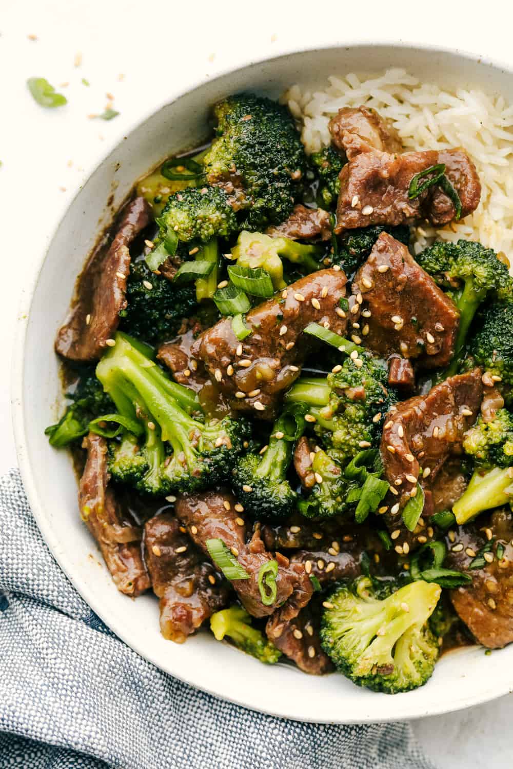 This beef and broccoli takes just minutes to toss in the slow cooker, and itโs hands-down one of my top recipes on the site! The beef turns melt-in-your-mouth tender, and the flavor is totally next level! Plated beef and broccoli with ruce and sesame seeds.