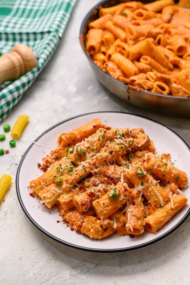 This spicy chicken rigatoni is one of our family favorites and easy to make recipes that Spicy chicken rigatoni on a white dish with the skillet behind in the photo.