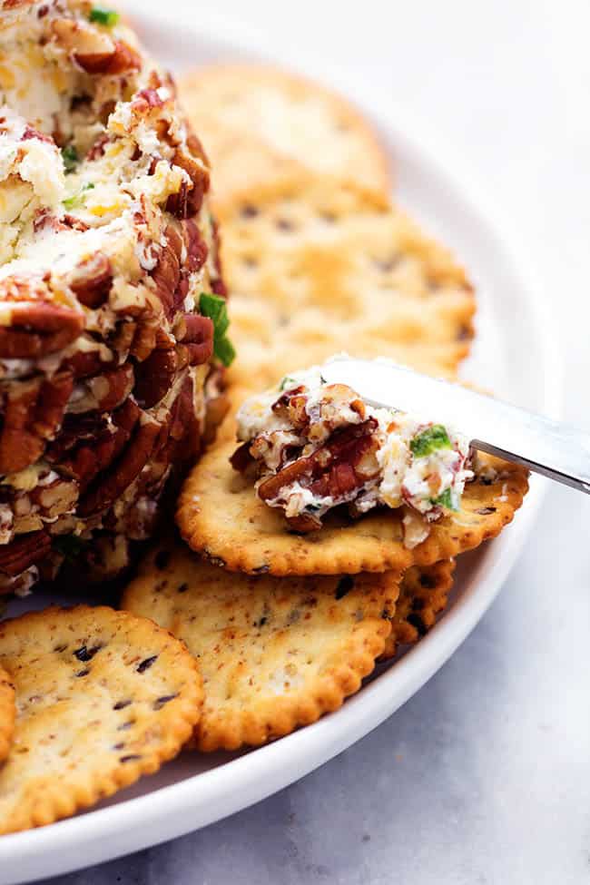This bacon ranch cheese ball will be your favorite go-to appetizer! The winning combination of bacon, ranch seasoning, and cheddar cheese really stands out in this tasty cheese ball. Serve with crackers and watch everyone devour it! Close view of a cracker with cheeseball spreading on top.