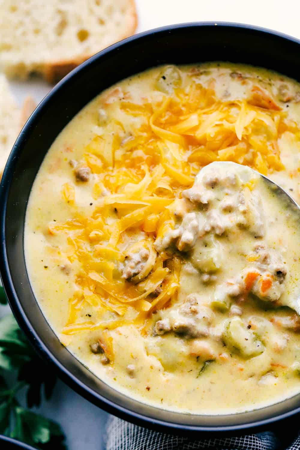 Award Winning Cheeseburger Soup is a thick and hearty soup with lean, tender ground beef, shredded carrots,ย dicedย celery and potatoes in a warm and creamy cheese soup. This is an award winning soup and it is excellent!ย Cheeseburger soup with a spoon.