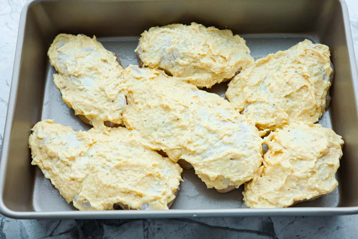 Parmesan baked chicken is so tender and juicy on the inside with a wonderful cheesy exterior. Your family will love the intense flavors, and you will love how quickly and easily this comes together! With only six ingredients and 10 minutes of prep, dinner will be served in no time! Overhead shot of chicken breasts with mayo mixture spread over the top.