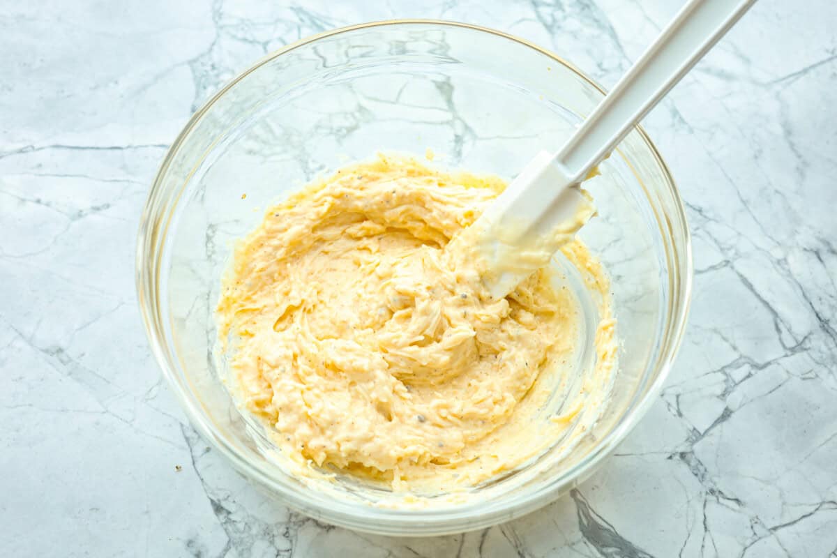 Parmesan baked chicken is so tender and juicy on the inside with a wonderful cheesy exterior. Your family will love the intense flavors, and you will love how quickly and easily this comes together! With only six ingredients and 10 minutes of prep, dinner will be served in no time! Overhead shot of mayo, cheese and seasonings mixed together in a glass bowl.