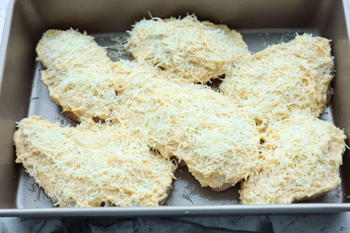 Parmesan baked chicken is so tender and juicy on the inside with a wonderful cheesy exterior. Your family will love the intense flavors, and you will love how quickly and easily this comes together! With only six ingredients and 10 minutes of prep, dinner will be served in no time! Overhead shot of chicken with mayo mixture and parmesan cheese sprinkled over the top.