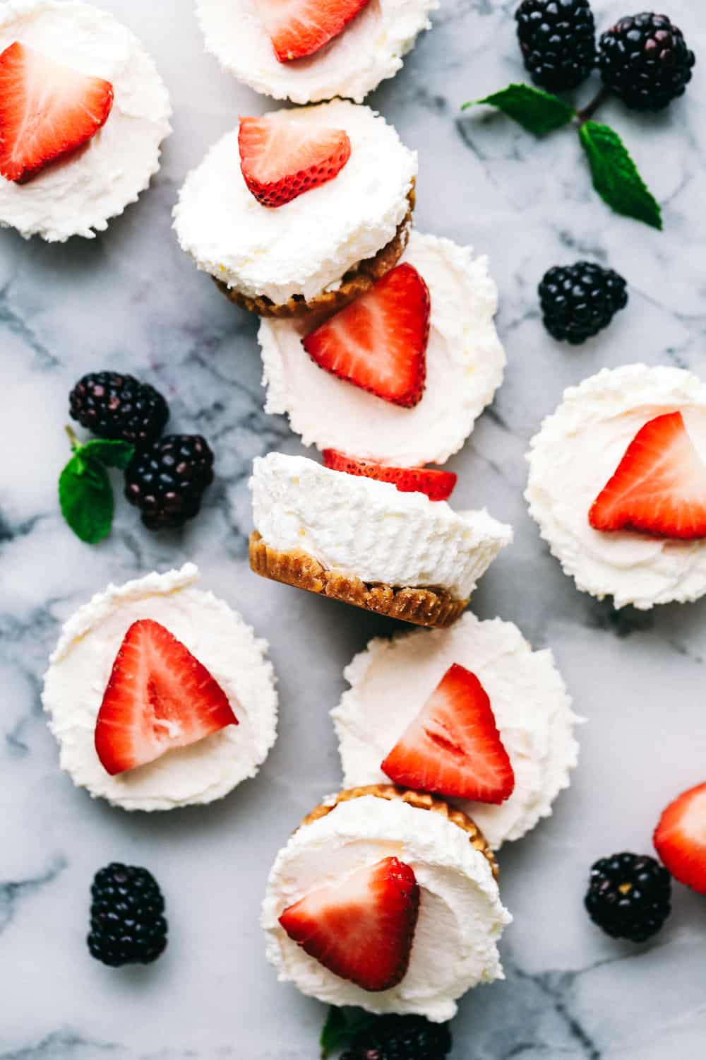 Cheesecake without the guilt! These skinny mini cheesecakes are light, creamy and will melt in your mouth with every bite! This low-calorie dessert is just what you need to satisfy your sweet tooth and stick to your New Year's resolution. Skinny Mini Cheesecake bites on a marble counter with blackberries inbetween.