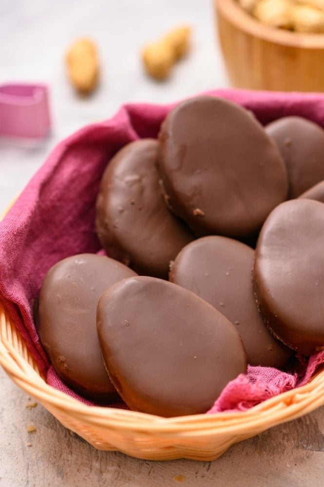 These homemade Reese's eggs are to die for!! With a creamy peanut butter center inside a thick, rich chocolate covering, these make the best Easter treat! A basket (with a pink towel) full of reese's Easter eggs.