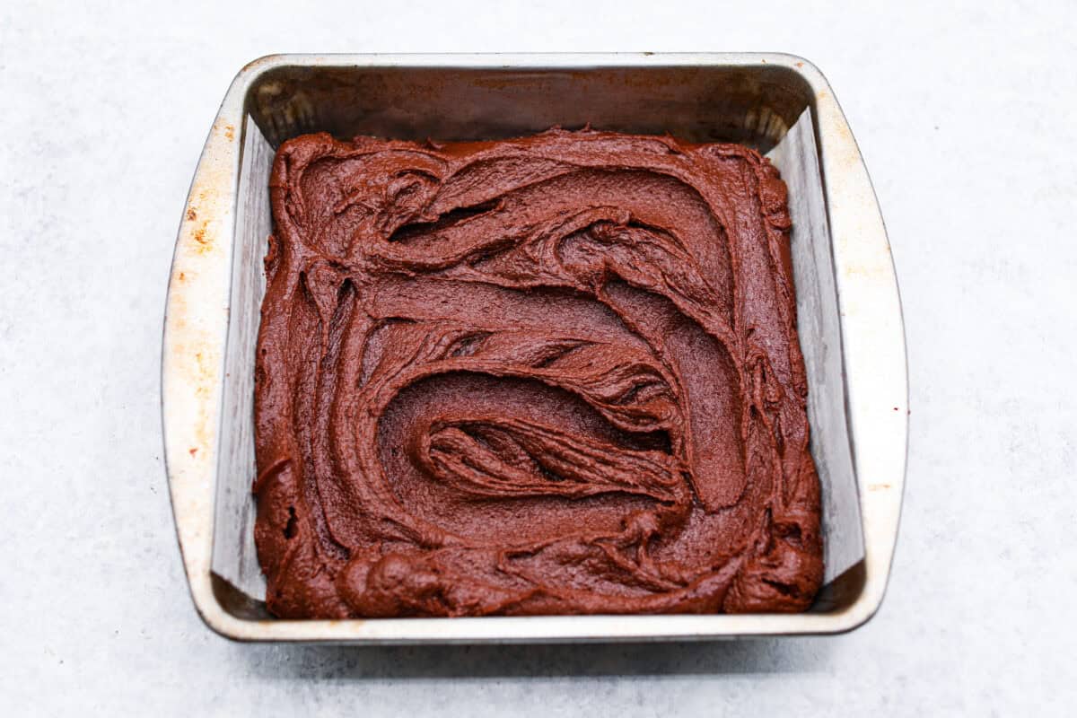 The best of both worlds collide in these peanut butter brownies! Fudgy homemade brownies are swirled with a sweet peanut butter mixture. The combination is an explosion of rich decadent flavors! Fourth photo of the brownie batter spread into a baking pan.