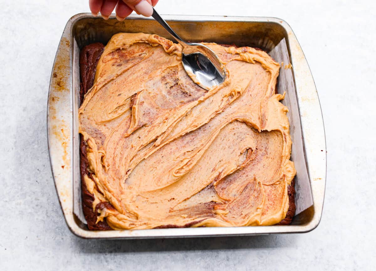 The best of both worlds collide in these peanut butter brownies! Fudgy homemade brownies are swirled with a sweet peanut butter mixture. The combination is an explosion of rich decadent flavors! Eighth photo of the peanut butter mixture being swirled into the brownie batter.