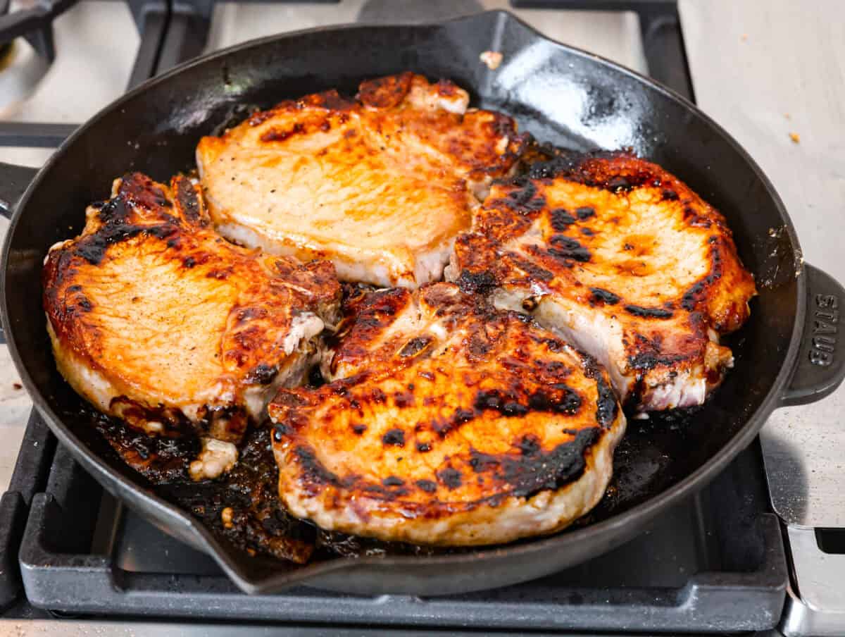 These brown sugar glazed pork chops are incredibly flavorful and delicious. Your family will love the salty pork smothered in a sweet brown sugar glaze. The crispy seared textured with the sweet sauce dripping down each bite will have you begging for more! Overhead shot of pork seared in a skillet.