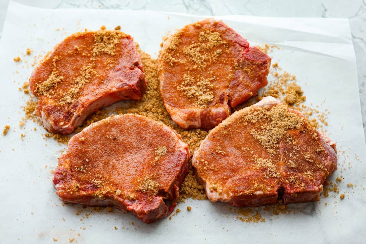 These brown sugar glazed pork chops are incredibly flavorful and delicious. Your family will love the salty pork smothered in a sweet brown sugar glaze. The crispy seared textured with the sweet sauce dripping down each bite will have you begging for more! Overhead shot of pork chops covered in brown sugar glaze rub.