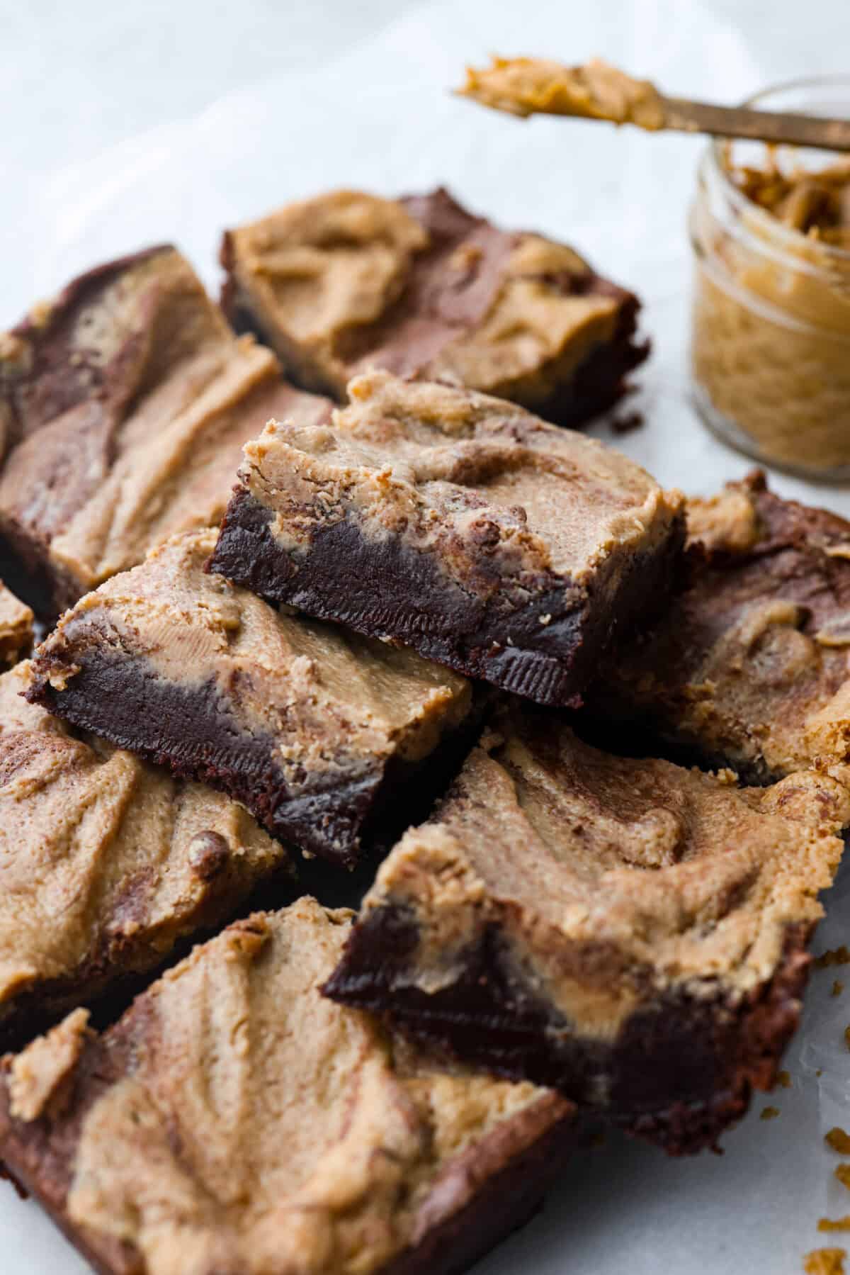 The best of both worlds collide in these peanut butter brownies! Fudgy homemade brownies are swirled with a sweet peanut butter mixture. The combination is an explosion of rich decadent flavors! Close side view of a small stack of peanut butter brownies.