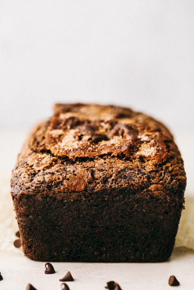 Chocolate Zucchini Bread is moist, sweet and filled with a hidden gem! It bakes perfectly and has a beautiful cracked sugar crust topping! Chocolate zucchini bread with chocolate chips scattered on bottom.