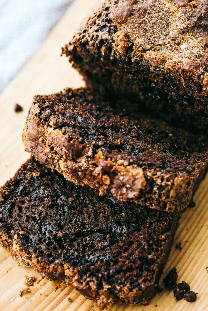 Chocolate Zucchini Bread is moist, sweet and filled with a hidden gem! It bakes perfectly and has a beautiful cracked sugar crust topping! Chocolate zucchini bread sliced on a cutting board.