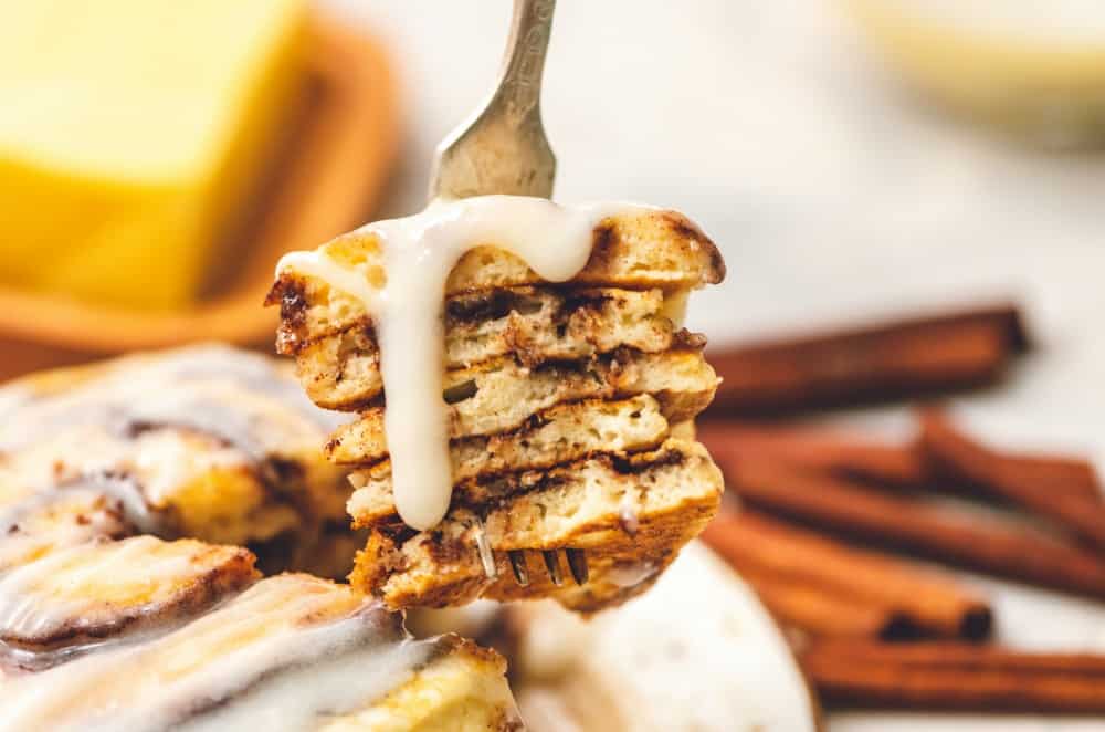 Cinnamon Roll Pancakes are aย delicious homemadeย pancake mix swirled with cinnamon roll filling and drizzled with aย delicious cream cheese glaze. These are pureย deliciousness!ย Cinnamon roll pancakes layered on top of each other with the cream cheese glaze.