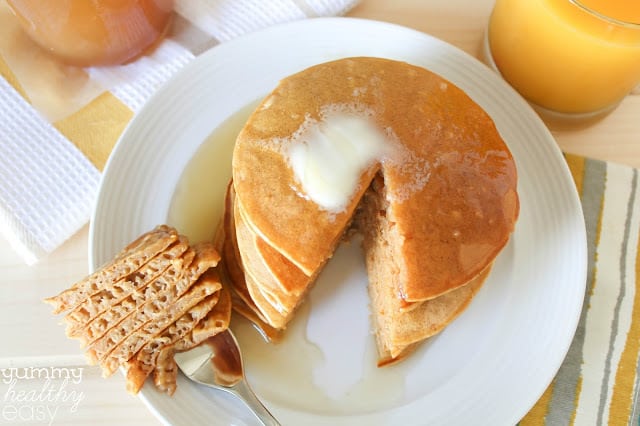 Delicious Pumpkin Pancakes made with healthier ingredients! Stack of pumpkin pancakes with one bite cut out and on a fork.